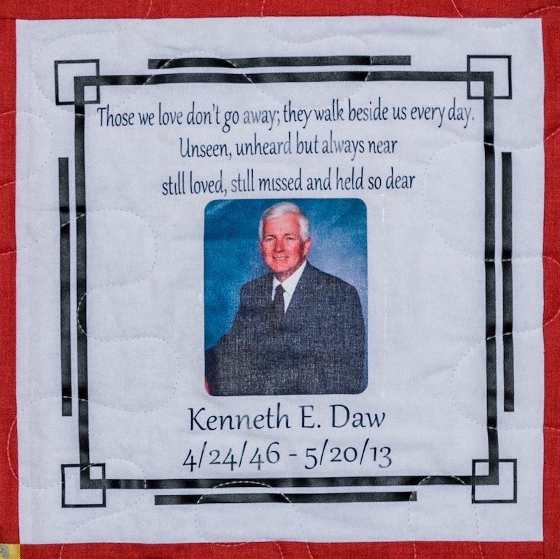 Quilt square for Kenneth E Daw with a portrait of Kenneth at the center and text reading: Those we love don’t go away, they walk beside us every day. Unseen, unheard but always near still loved, still missed and held so dear.