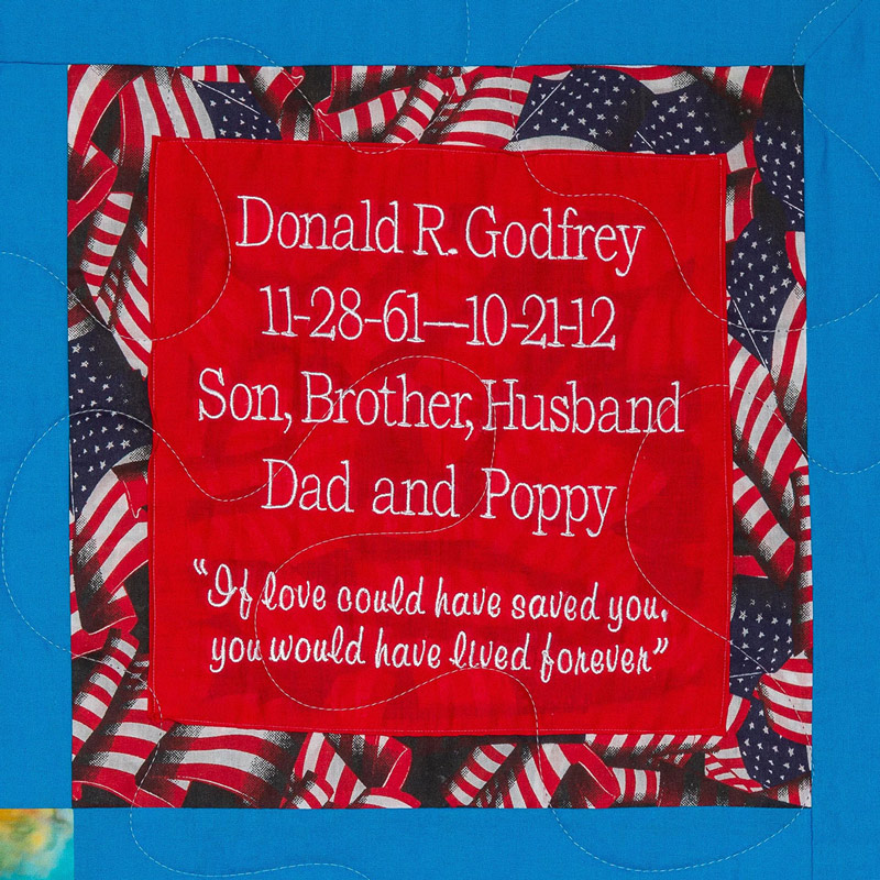 Quilt square for Donald R. Godfrey with American flags in the background and text read: If love could have saved you, you would have lived forever.