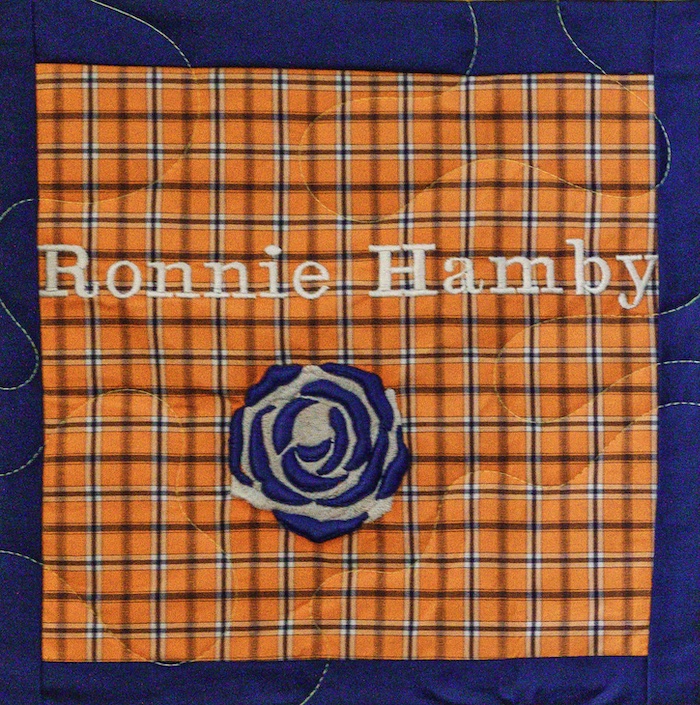 Quilt square for Ronnie Hamby with orange patchwork and a blue rose