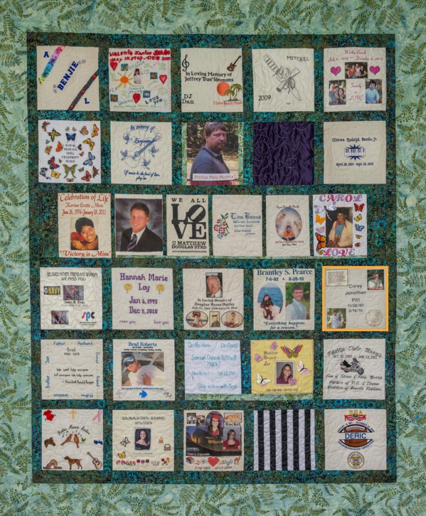 Colorful green quilt with foliage pattern and 31 unique squares featuring donor names, photos, and memories