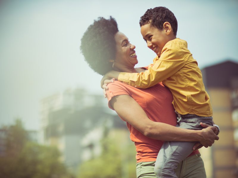 Woman holds and embraces boy outside at dawn