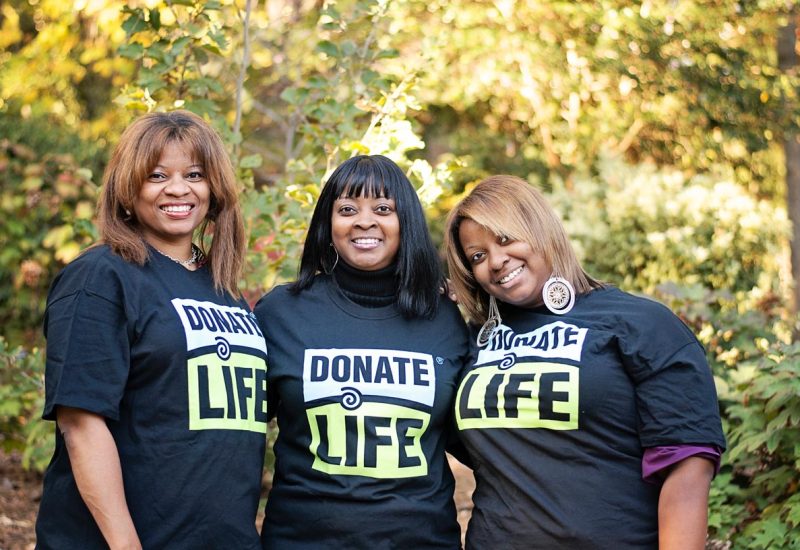 Three woman pose together while wearing donate life t-shirts outside