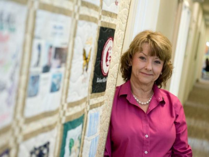 A woman stands next to large yellow quilt