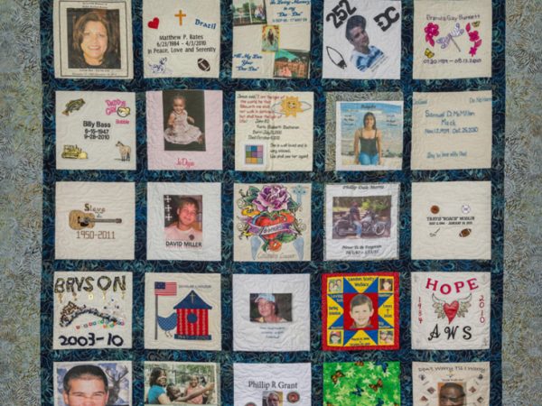 Colorful green, blue, and yellow quilt with foliage pattern and 34 unique squares featuring donor names, photos, and memories