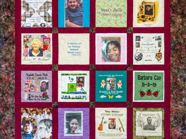 Colorful red quilt with 16 unique squares featuring donor names, photos, and memories
