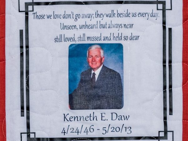 Quilt square for Kenneth E Daw with a portrait of Kenneth at the center and text reading: Those we love don’t go away, they walk beside us every day. Unseen, unheard but always near still loved, still missed and held so dear.
