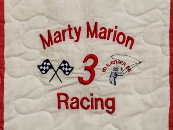 Quilt square for Marty Marion with racing flags, the number 3, and a fisherman. Text reading: Racing. I’d rather be fishing.