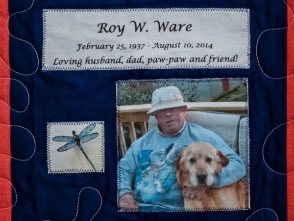 Quilt square for Roy Ware with a dragon fly and a photo of Roy with his dog. Text reading: loving husband, dad, paw-paw and friend.
