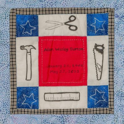 Quilt square for Alan Burton with patches for a pair of scissors, a hammer, saw, and ruler.
