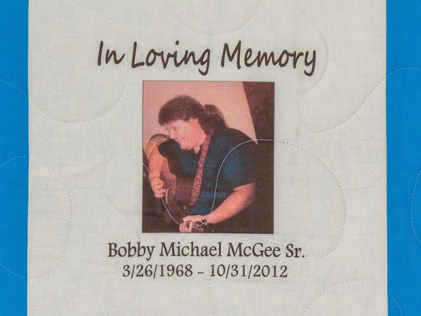 Quilt square for Bobby Michael McGee Sr. with a photo of Bobby playing guitar.