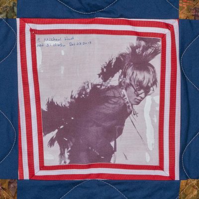 Quilt square for Carles Michael Hunt with photo of Carles in center of a red and blue pattern
