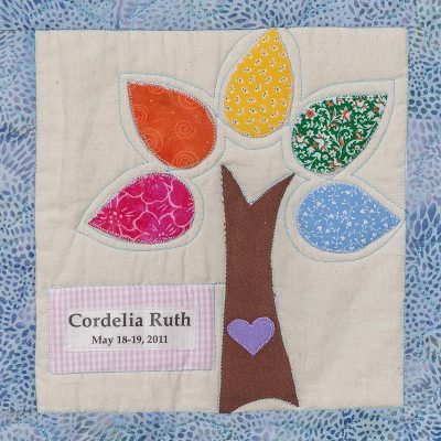 Quilt square for Cordelia Casper with a tree with colorful leaves and a purple heart.