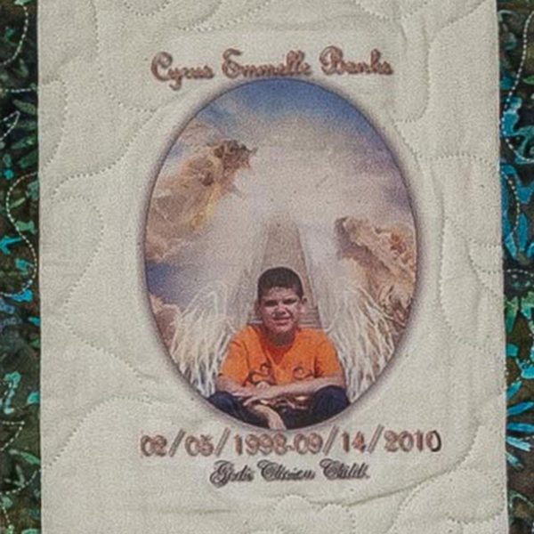 Quilt square for Cyrus Banks with photo of Cyrus sitting front of a glowing light.