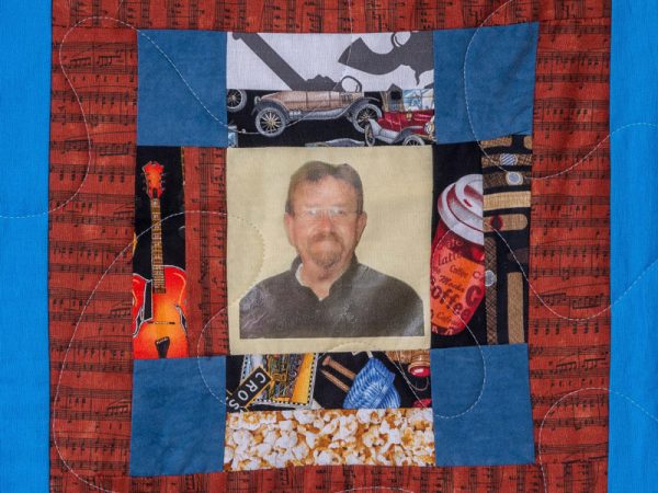 Quilt square for Danny Spence with a photo of Danny and a collage of guitars, coffee, cars, and popcorn.