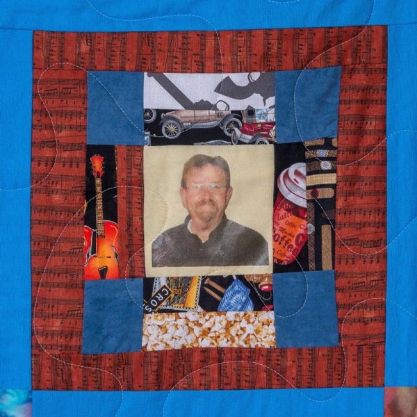 Quilt square for Danny Spence with a photo of Danny and a collage of guitars, coffee, cars, and popcorn.