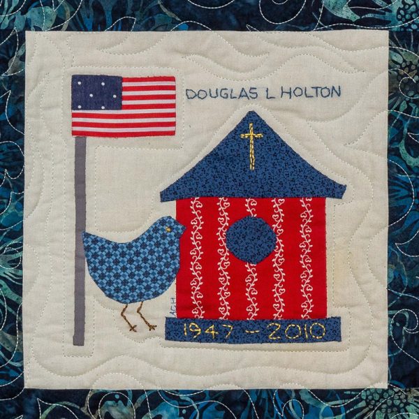 Quilt square for Douglas L Holton with an American flag, a bird feeder with a cross, and a bird.