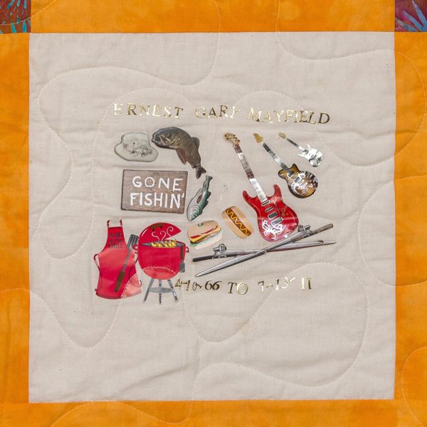 Quilt square for Ernest Mayfield with patches of fishing gear, a grill, grill gear, hotdogs, and burgers, guitars, and text reading gone fishin’.