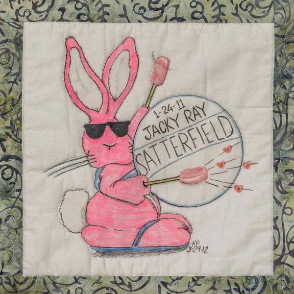 Quilt square for Jacky Satterfield with a pink rabbit beating a drum.