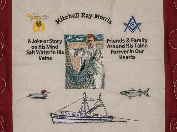 Quilt square for Mitchell Morris with small patches and text reading: A joke or story on his mind, salt water in his veins. Friends & family around his table forever in our hearts. And a patch of Mitchell holding a fishing net.