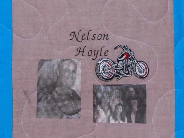 Quilt square for Nelson Hoyle with pictures of Nelson and his family, and a patch of a motorcycle.