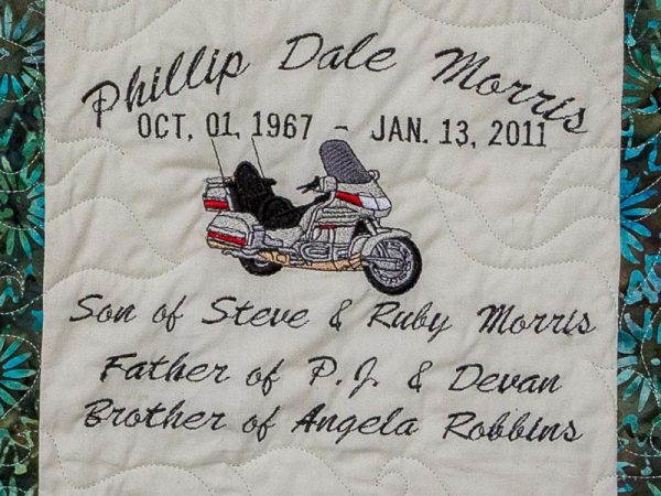 Quilt square for Phillip Morris with a patch of a motorcycle and text reading: Son of Steve & Ruby Morris, Father of P.J & Devan, Brother of Angela Robbins.