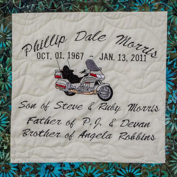Quilt square for Phillip Morris with a patch of a motorcycle and text reading: Son of Steve & Ruby Morris, Father of P.J & Devan, Brother of Angela Robbins.