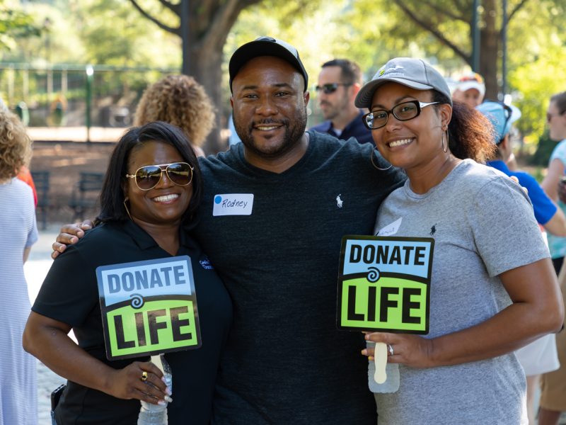 Three HonorBridge staff members holding Donate Life Signs at an event
