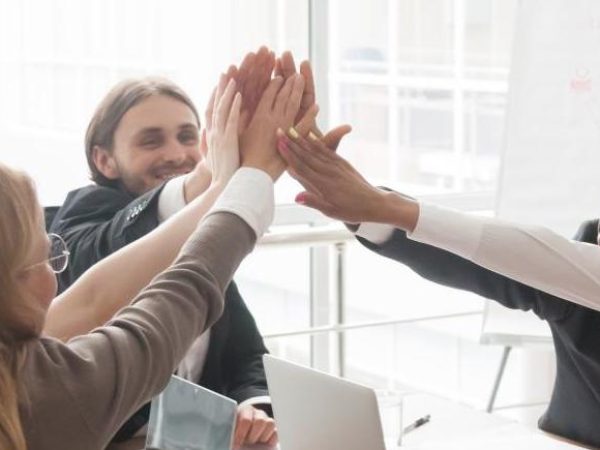 Diverse group of coworkers high-five in the office.