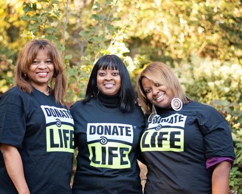 Three woman pose together while wearing donate life t-shirts outside