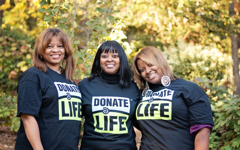 Three woman pose together while wearing donate life t-shirts outside