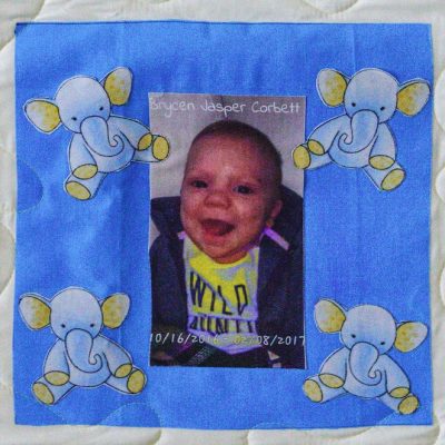 Quilt square for Brycen Corbett with a portrait of a baby Brycen and patches of elephants