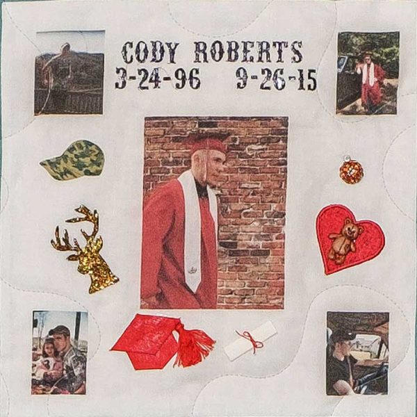 Quilt square for Cody Roberts with a photo of Cody at graduation and patches of hunting clothes, deer, and a symbol of a heart and bear.
