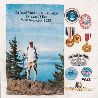 Quilt square for Donald Patrick Crockett with a photo of Daniel hiking and numerous awards and medals on the side.