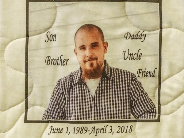 Quilt square for Dustin Wilke with a portrait of Dustin and text reading: Son, Brother, Daddy, Uncle, Friend, Forever in Our Hearts