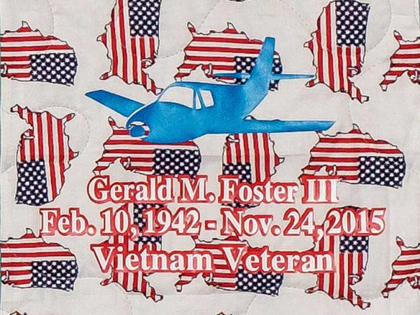 Quilt square for Gerald Foster with a plane in the center a pattern of flags and the USA in the background