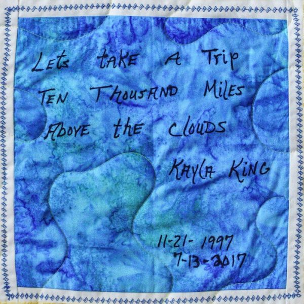 Quilt square for Kayla King with text reading: Let’s take a trip ten thousand miles above the clouds