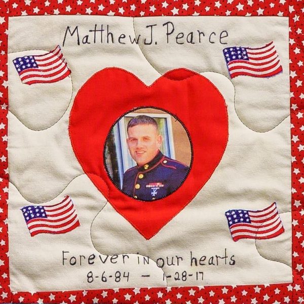 Quilt square for Matthew J. Pearce with a portrait of Matthew in his Marine Corps uniform centered in a heart and surrounded by patches of the American flag.
