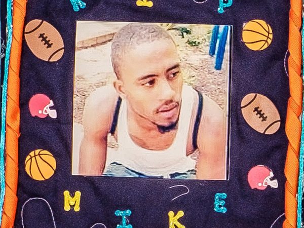 Quilt square for Michael Richardson with a photo of Mike at the center surrounded by basketballs, footballs, and football helmets. Text reading: RIP Mike.