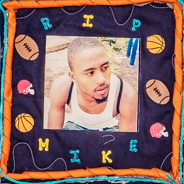 Quilt square for Michael Richardson with a photo of Mike at the center surrounded by basketballs, footballs, and football helmets. Text reading: RIP Mike.