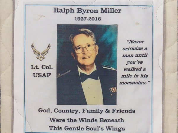 Quilt square for Ralph Miller with a photo of Ralph and text reading: Lt. Col. USAF, Never criticize a man until you’ve walked a mile in his moccasins. God, Country, Family & Friends Were the Winds Beneath this Gentle Soul’s Wings.