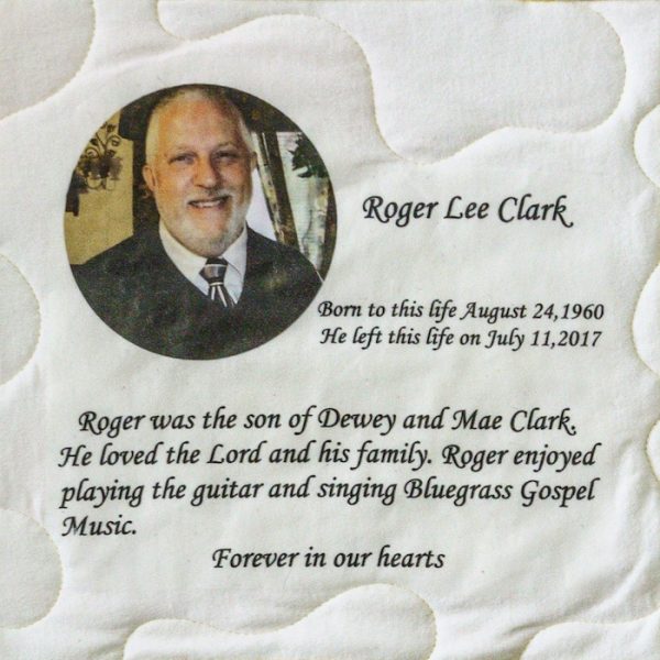 Quilt square for Roger Clark with portrait of Roger and text reading: Roger was the son of Dewey and Mae Clark. He loved the Lord and his family. Roger enjoyed playing the guitar and singing bluegrass gospel music.