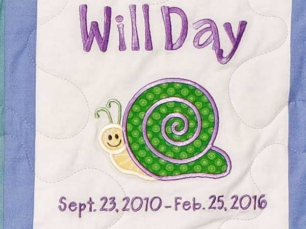 Quilt square for William Day with an illustration of a happy snail at the center