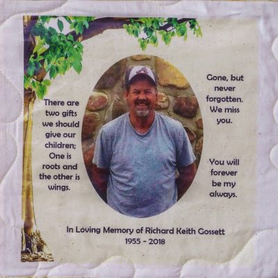 Quilt square for Richard Gossett with outdoor portrait of Richard under a patch of a tree and text reading: There are two gifts we should give our children; one is roots and the other is wings. Gone, but never forgotten. We miss you. You will forever be my always.