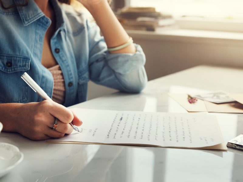 A woman writes a letter at her desk