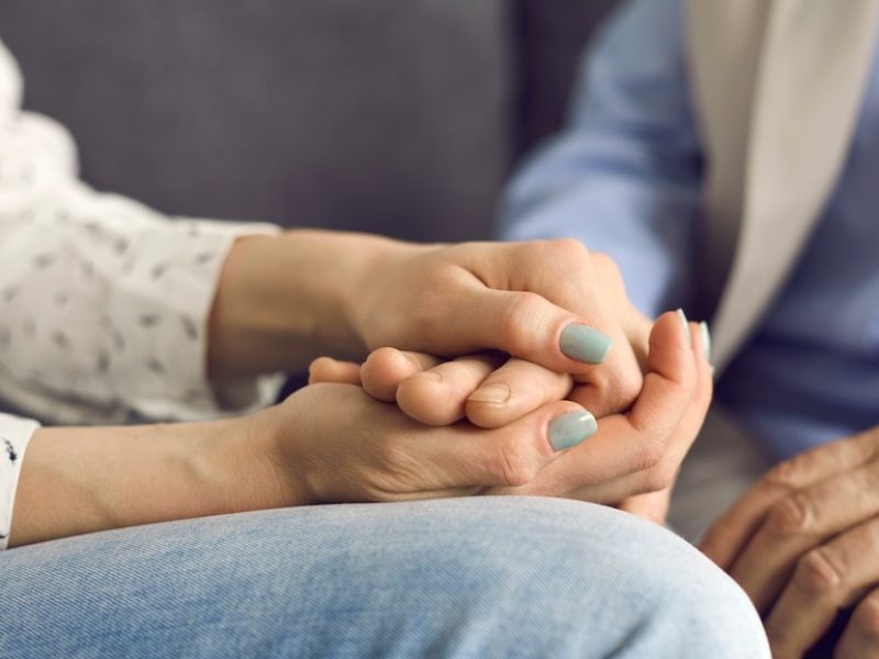 Loving young woman holding her senior mother's hand comforting and supporting her